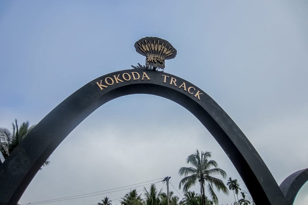 Archway marking the start of the Kokoda Track with a decorative emblem, a significant historical and hiking site. Tackling the Kokoda Trail is one of the most challenging things to do in Papua New Guinea.