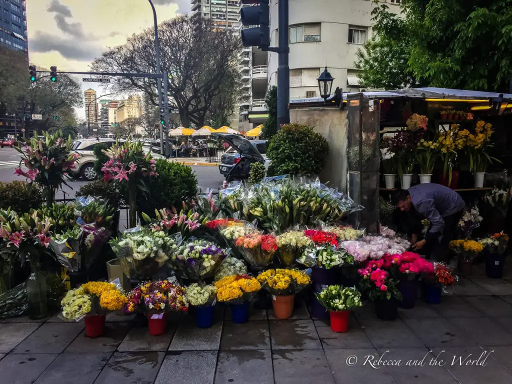 A vibrant street flower market in Buenos Aires with an array of colorful bouquets and a vendor arranging the displays. Figuring out the best areas to stay in Buenos Aires can be challenging - but there's lot of great neighbourhoods to choose from.