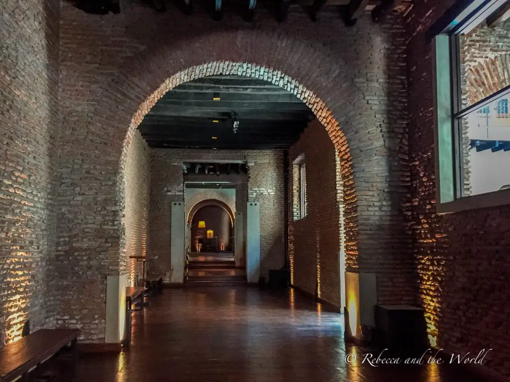 A dimly lit corridor with brick walls and arched openings, evoking a sense of historic architectural design. El Zanjon de Granados is a fascinating place to visit in San Telmo, Buenos Aires.