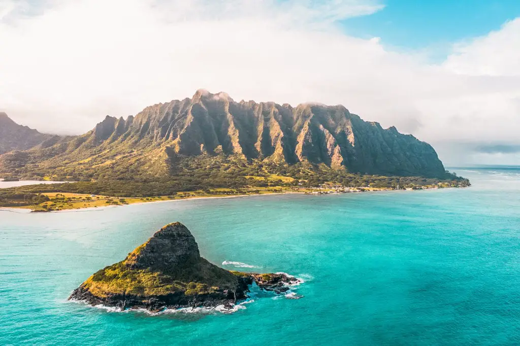 A breathtaking aerial view of a mountainous coastline, with a prominent, rocky islet close to the shore and turquoise waters - this is Oahu, one of Hawaii's stunning islands. Oahu, Hawaii, is one of the most beautiful places to visit in the United States.