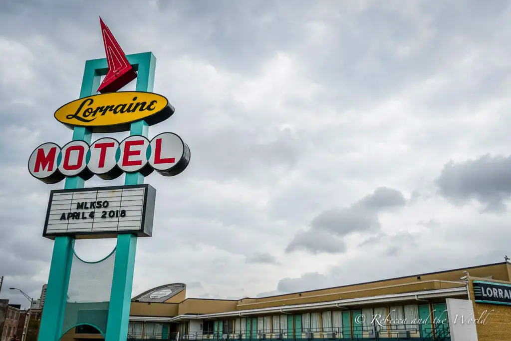 The iconic sign of the Lorraine Motel, featuring a bright neon design with a red arrow. The marquee displays 