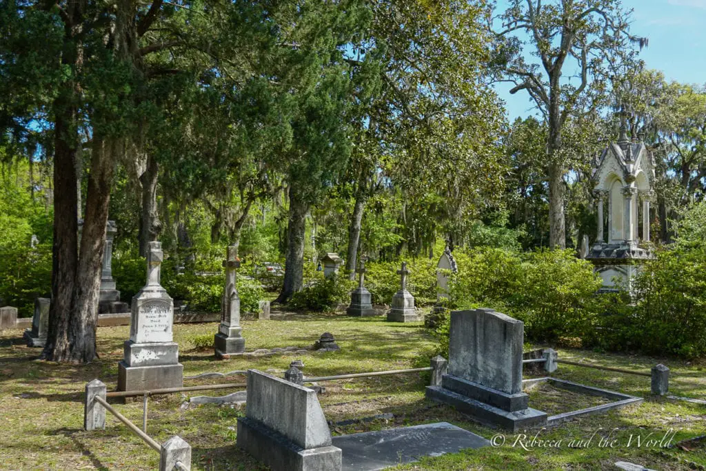 A graveyard in Savannah, Georgia, has grey tombs surrounded by green grass and trees