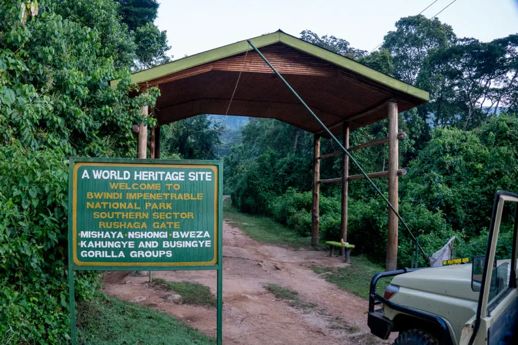 A wooden sign at the entrance to Bwindi Impenetrable National Park, announcing various gorilla groups, with a vehicle parked on the side and forest in the background. Gorilla trekking is an incredible experience and one you should definitely do if you have the inclination, time and money.