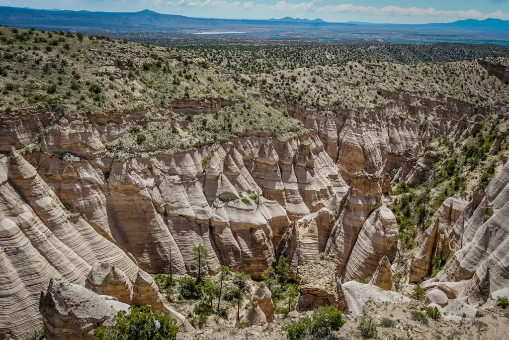 The Kasha-Katuwe Tent Rocks National Monument, featuring unique cone-shaped rock formations with horizontal striations under a bright blue sky. This is a must-visit on your New Mexico itinerary.