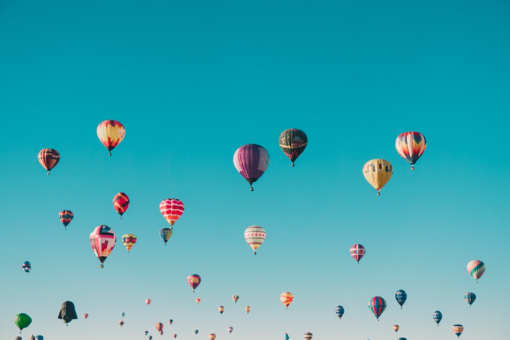 Dozens of colourful hot air balloons in a cloudless blue sky