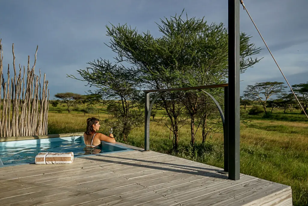 Woman - the author of this article - relaxing in an infinity pool overlooking a savannah landscape with sparse trees under a clear sky. This was an amazing lodge I stayed in while visiting Tanzania.