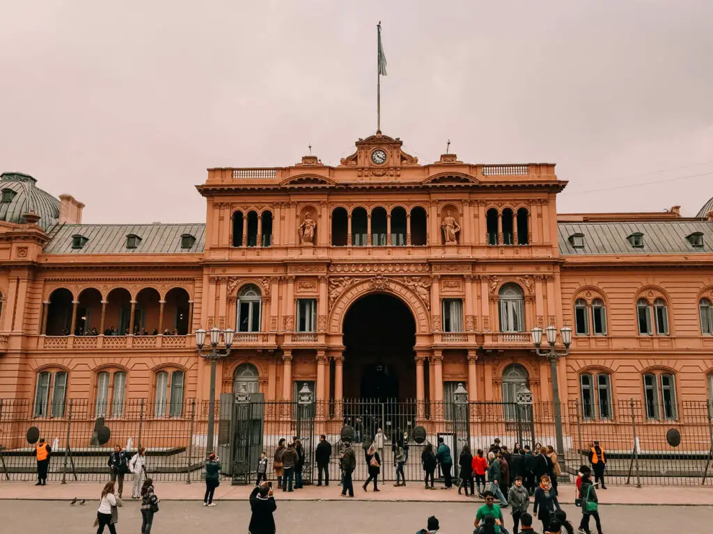 The Casa Rosada in Buenos Aires is a grand pink-washed building that is Argentina's version of the White House. People are milling about in front of the building, taking photos