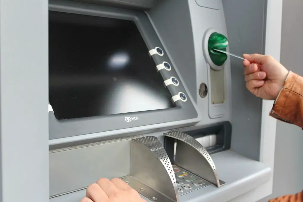 An unseen person inserts a card into an ATM machine. ATMs in Argentina have high fees and low withdrawal rates, so it's important to know about money in Argentina tips before you visit.