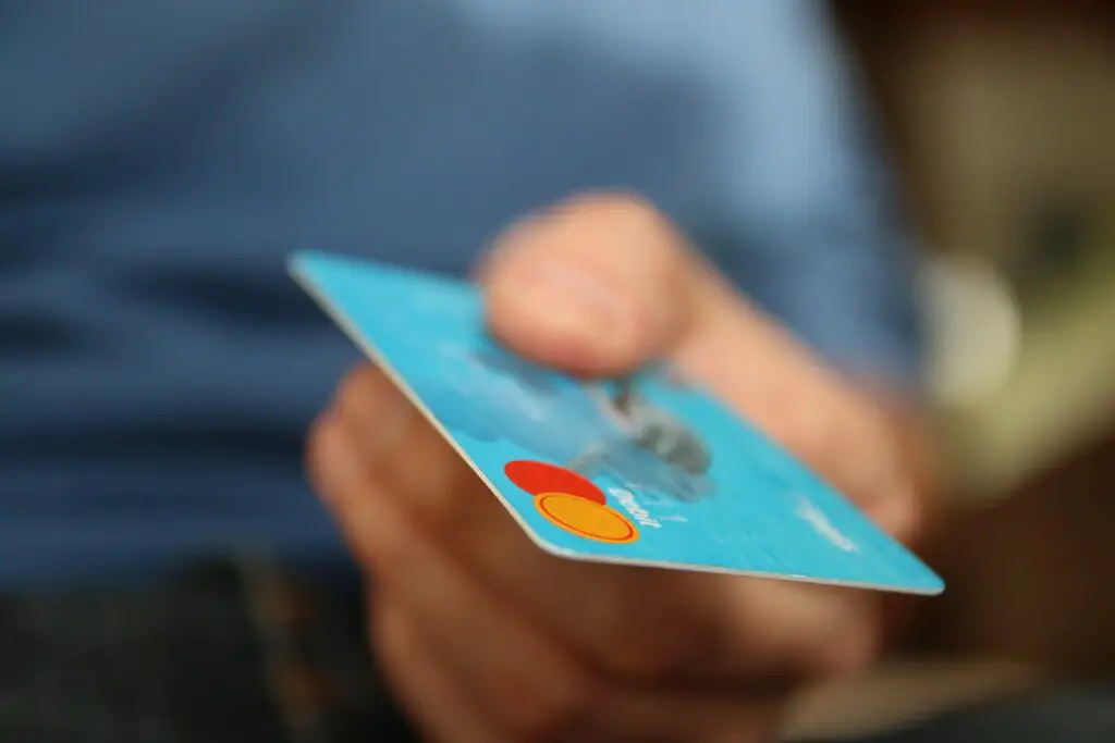 A blurred hand holds out a blue credit card.