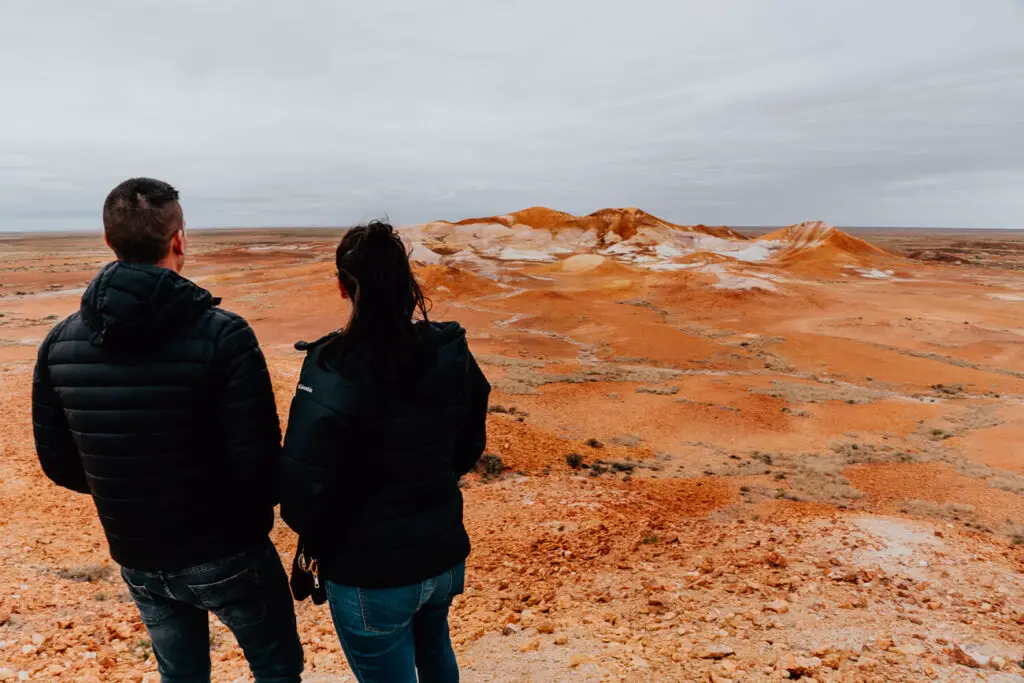 A man and woman - both in black jackets and jeans - look over the Kanku-Breakways Conservation Park in Coober Pedy