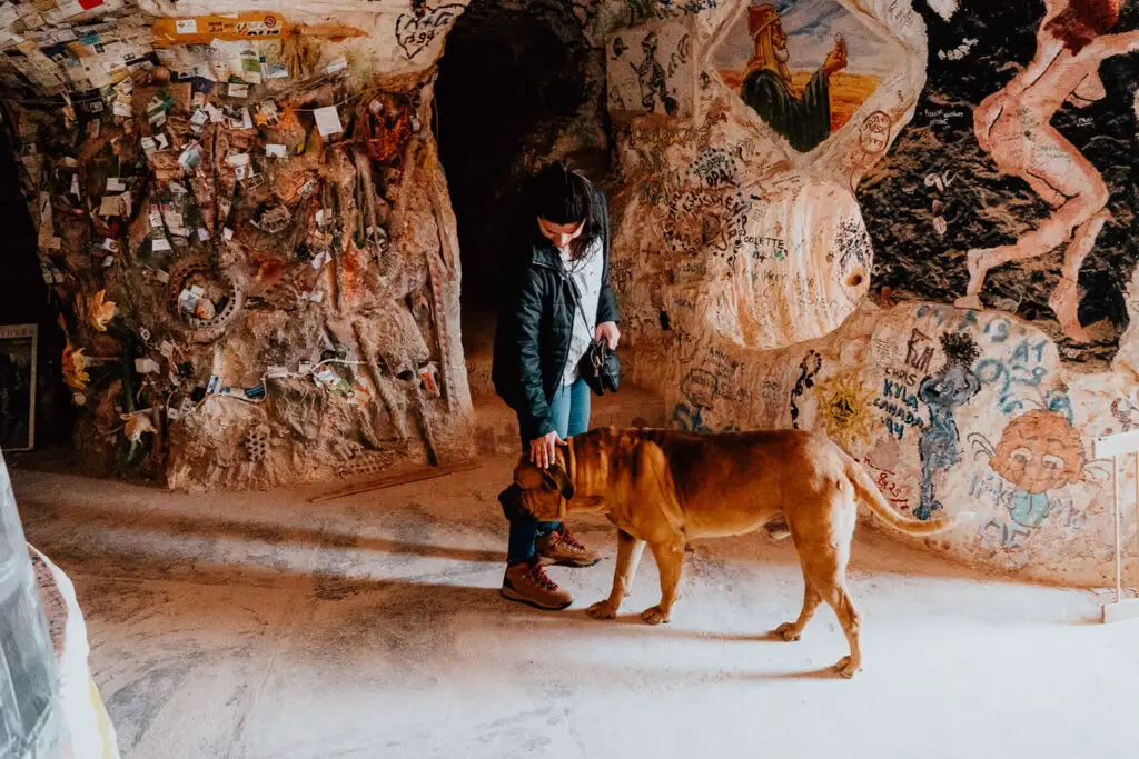 A woman in black jacket and jeans pats a large brown dog in Crocodile Harry's in Coober Pedy.