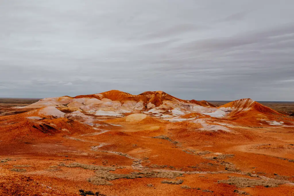 A series of hills emerge from the red, orange and white earth in Coober Pedy, South Australia
