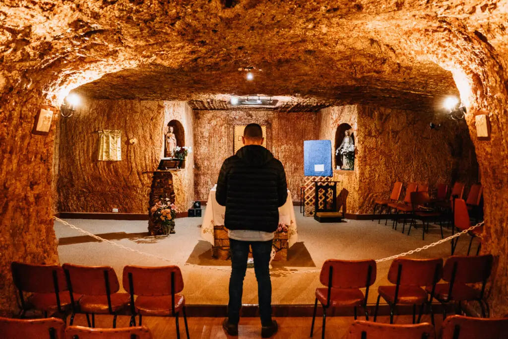 A man stands in front of the altar at the St Peter & Paul Church in Coober Pedy. It's one of the must-visit underground churches in Coober Pedy