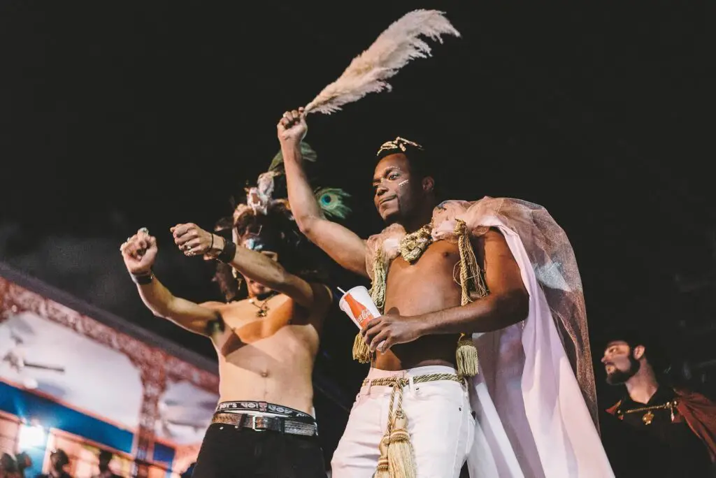Two shirtless men dancing on what appears to be a float during Mardi Gras in New Orleans, Louisiana