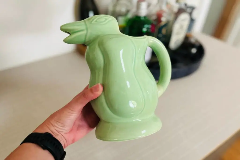 A unique green ceramic pitcher shaped like a penguin, a popular artisanal item often found in Buenos Aires shopping markets. This handmade piece is an example of what to buy in Buenos Aires to bring home a touch of local craftsmanship.