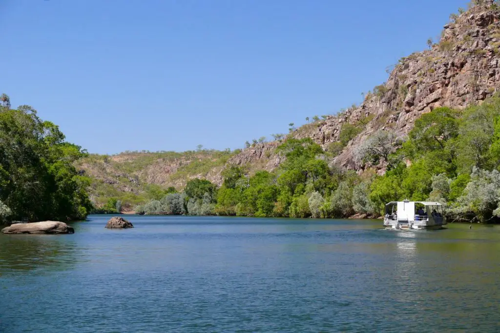 View of Nitmiluk Gorge from the water, showing the Katherine River surrounded by rocky gorge walls and a cruise boat heading along the water.