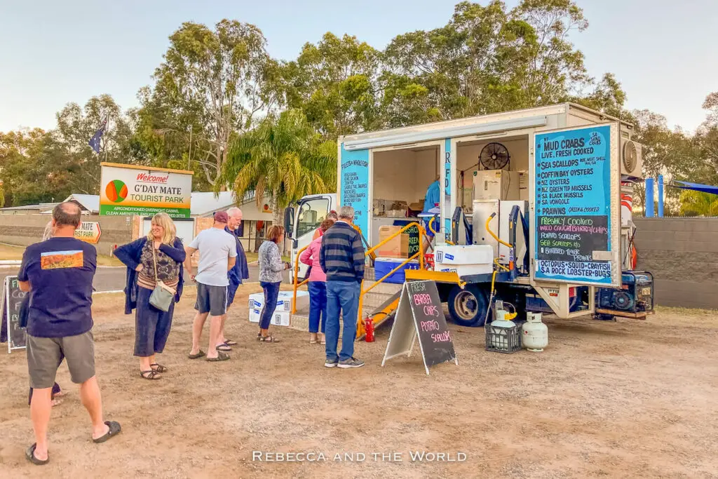 A food truck with a crowd of people lined up to order. The truck advertises various seafood items. The truck cooks fresh seafood out the front of the Alice Springs Brewing Co.