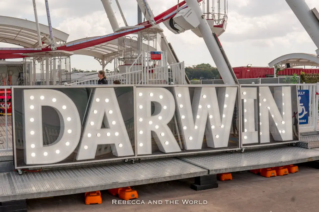 A large, illuminated "DARWIN" sign in front of a Ferris wheel. The letters are in capital form and lit with light bulbs, creating a focal point against the structures of the amusement ride and the daytime sky. Stokes Hill Wharf is one of the more touristy places to visit in Darwin, but it's got great views and restaurants.