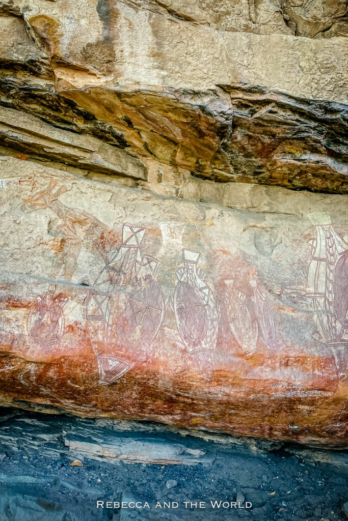 Ancient rock art on a sandstone wall in Kakadu National Park, showing detailed indigenous figures and animals in red and white ochre.