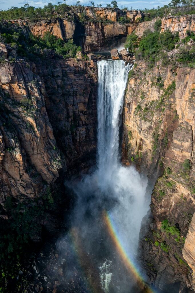 A breathtaking aerial view of Kakadu National Park showcasing the majestic Jim Jim Falls amidst the rugged cliffs and lush greenery.