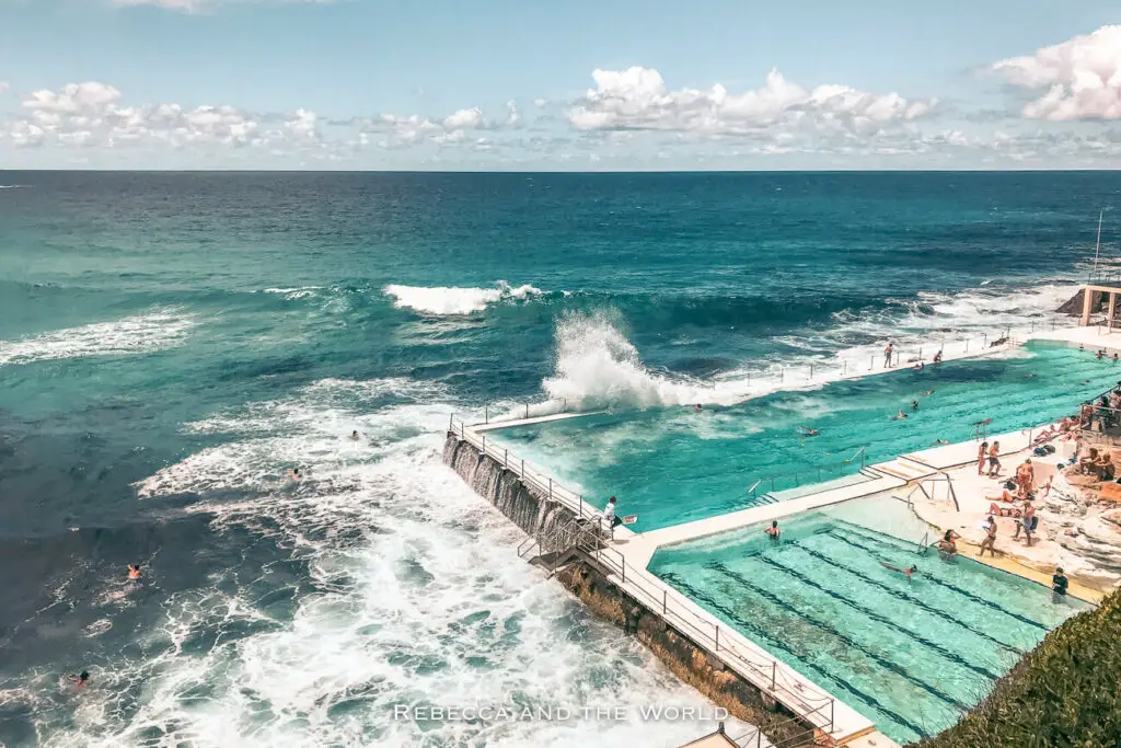 Bondi Icebergs ocean pool filled with swimmers, with waves crashing over the side on a sunny day.