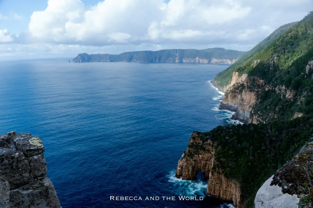Cliffside view of the Tasman Sea meeting the dramatic coastline of Tasmania with sheer cliffs and dense greenery. The Three Capes Track is one of the best hikes in Australia.