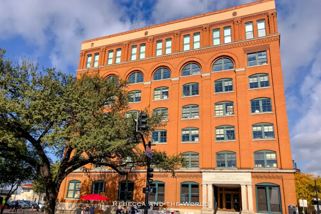 The red-brick, multi-story former Texas School Book Depository building in Dealey Plaza, with a clear blue sky above. This museum is one of the most popular Dallas attractions and something to add to your Dallas itinerary if you're into history.