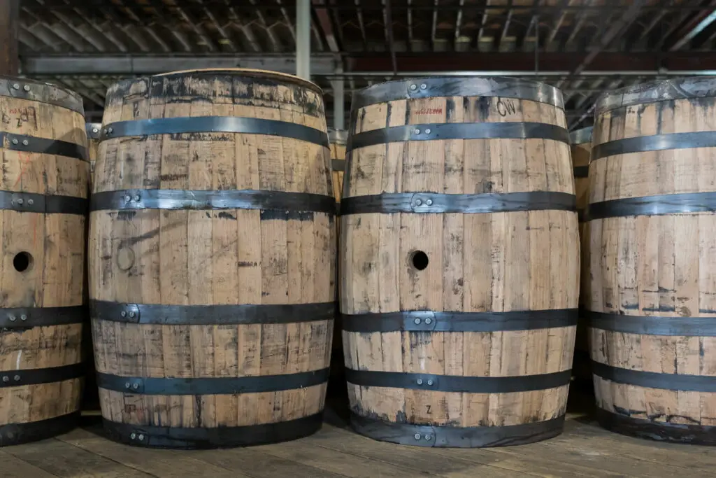 A row of aged wooden barrels with metal bands, possibly for wine or beer storage, indicative of Fredericksburg's local craft beverage scene.