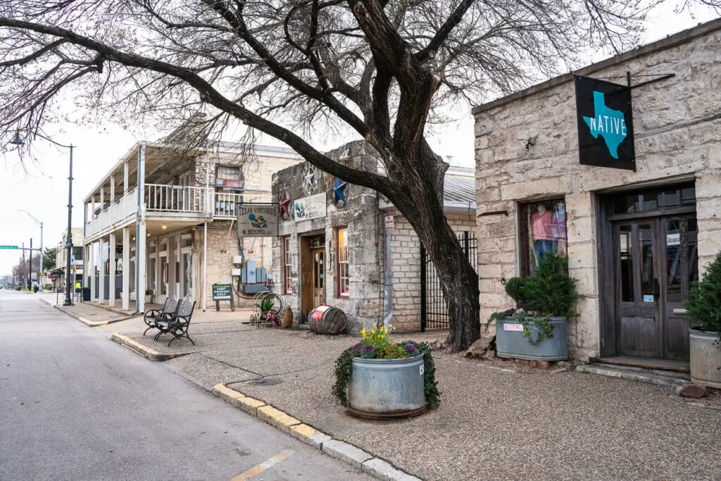 Historic storefronts with balconies line a quiet street in Fredericksburg, Texas, displaying the town's quaint and historic charm.