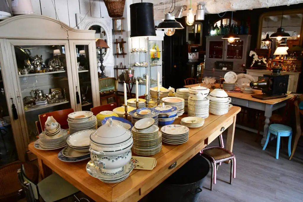 Interior of an antique shop with shelves of silverware, china, and various vintage items. Antique shopping is a must-do in Fredericksburg Texas.