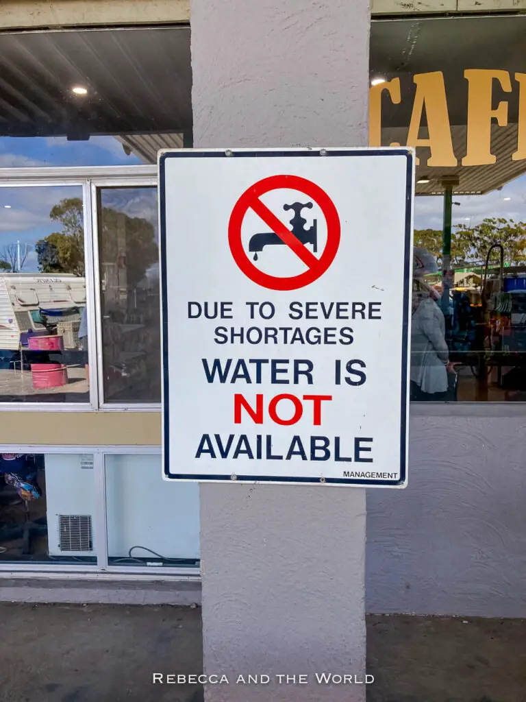 A sign posted outside a building reads, "Due to severe shortages, water is NOT available," with the word "NOT" emphasised in red. The sign also features a red circle with a slash over a tap, indicating no water access. When crossing the Nullarbor, come prepared with plenty of water.