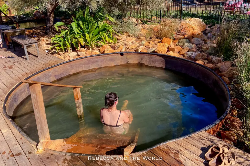 A person - the author of this article - relaxes in an artesian bore bath at Wooramel Riverside Retreat in Western Australia. The rustic wooden deck surrounding the bath and the vegetation create a tranquil setting for visitors seeking relaxation and rejuvenation during their half lap around Australia.