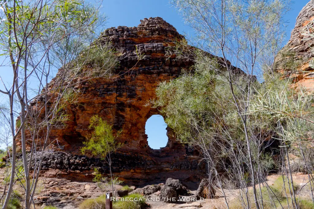 A natural rock arch within the Bungle Bungles in Purnululu National Park. The arch is formed by weathered rock, surrounded by sparse vegetation, illustrating the park's unique and varied landscape.
