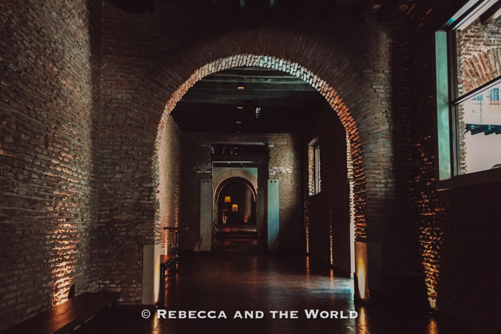 A dimly lit corridor with exposed brick walls and arched ceilings stretches into the distance. Soft lighting highlights the texture of the bricks and the walkway. El Zanjon is one of the most interesting things to do in San Telmo, Buenos Aires.
