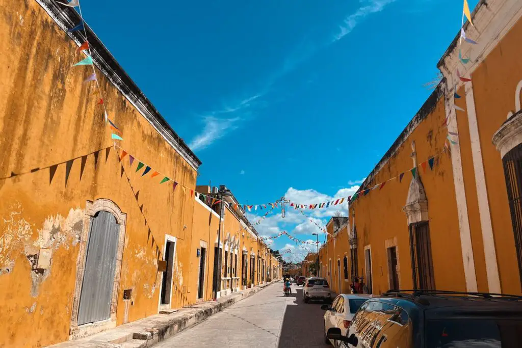 Bright yellow street in Izamal with bunting across the road, highlighting the charm of this Pueblo Mágico on a Yucatan travel route.
