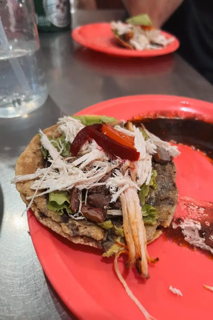 Traditional Yucatecan panucho with shredded meat, beans, and pickled vegetables, sampled during a food tour in Merida.