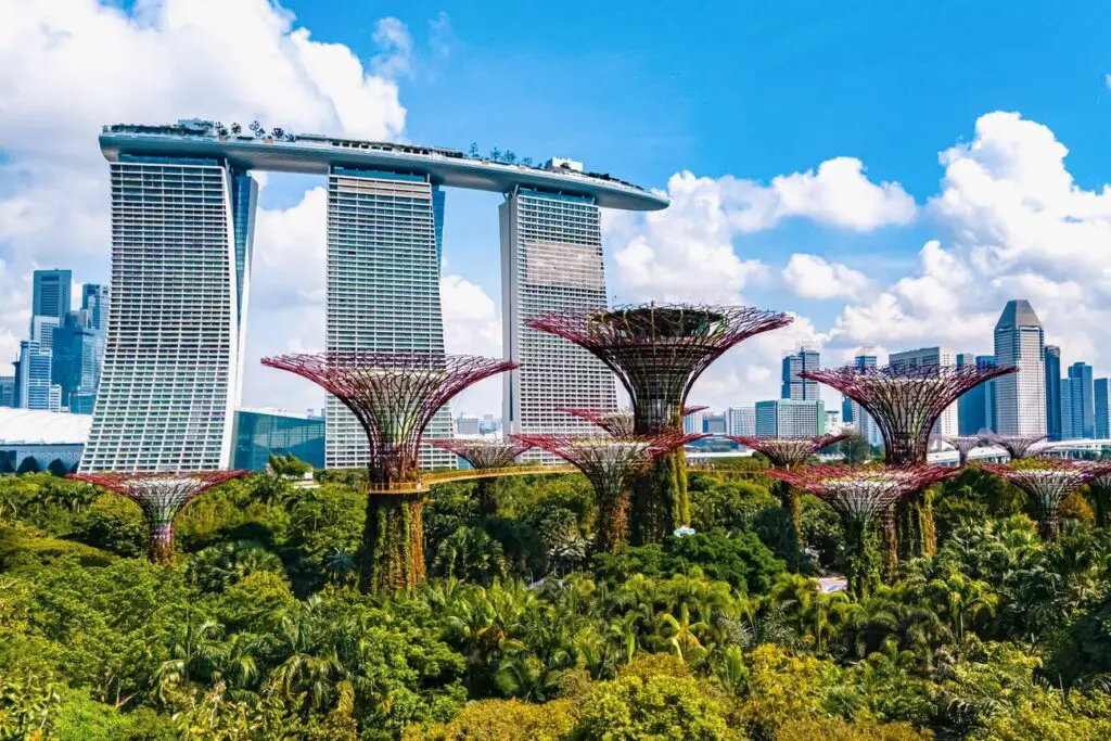 Panoramic view of Singapore’s Gardens by the Bay with futuristic Supertree Grove in the foreground and the iconic Marina Bay Sands hotel in the background, symbolizing Singapore’s blend of nature, architecture, and innovation.