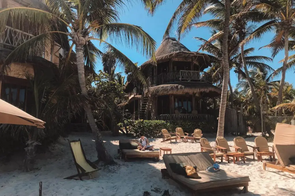 Alaya Tulum, a beachfront eco-resort with thatched-roof villas and lounge chairs on the sand in Tulum, a popular stop on a Yucatan itinerary.