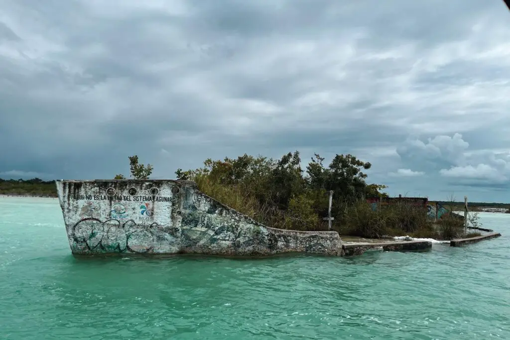 Ruins of an old structure emerging from the turquoise waters of Bacalar Lagoon, a unique and historic stop on a Yucatan itinerary.