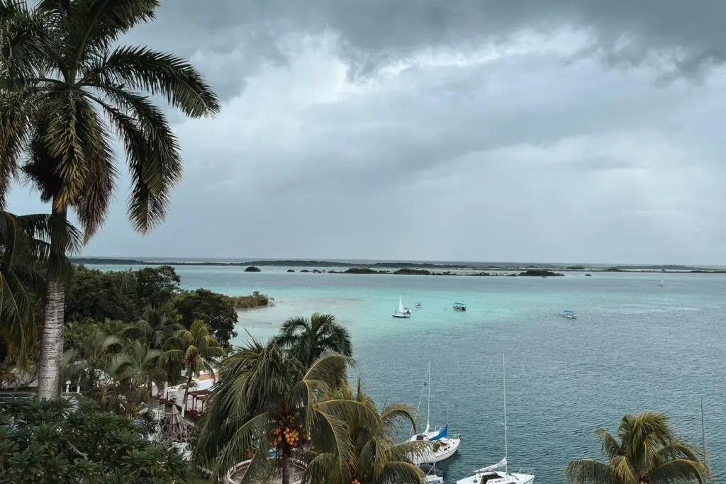 Palm trees and boats on the bright blue waters of Bacalar Lagoon, one of the most scenic highlights of a Yucatan itinerary.