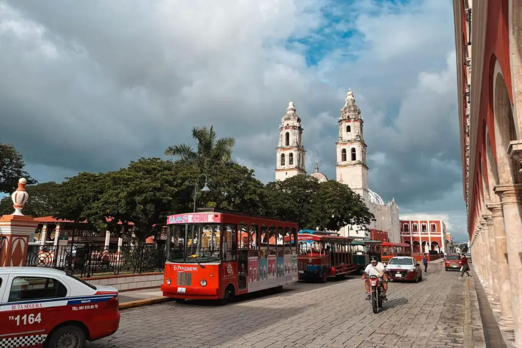 Red and blue tour trams parked in front of Campeche’s cathedral, a common sight when exploring the historic center on a Yucatan itinerary.