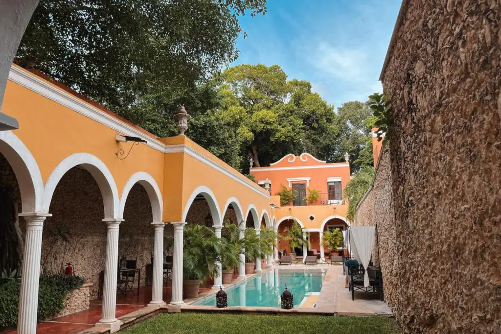 A charming colonial courtyard at Hacienda Merida, featuring a pool and bright yellow arches.