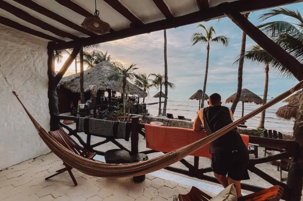 A man - the author's husband - relaxes on a beachfront porch with a hammock on Isla Holbox, an option for one of the beaches to visit in the Yucatan Peninsula.