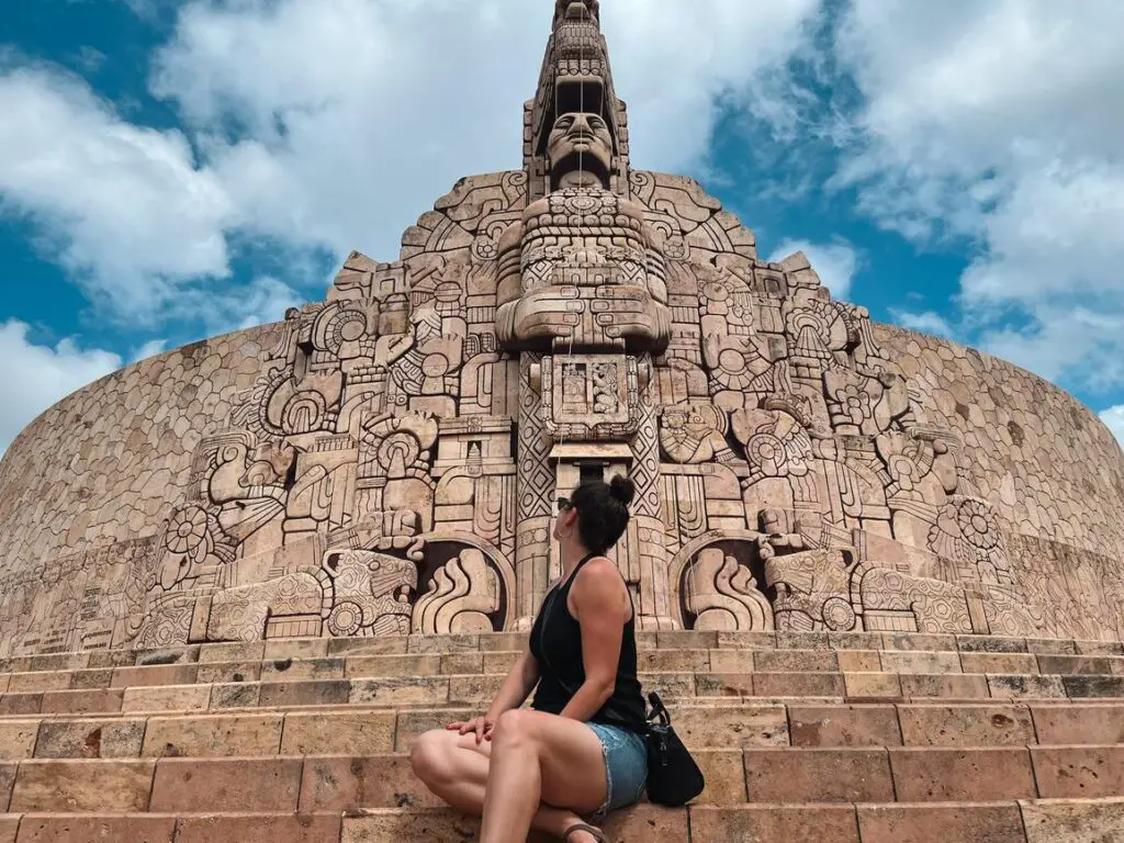 Woman - the author of this article - sitting on the steps of Monumento a la Patria in Merida, a key cultural stop on any Yucatan itinerary.