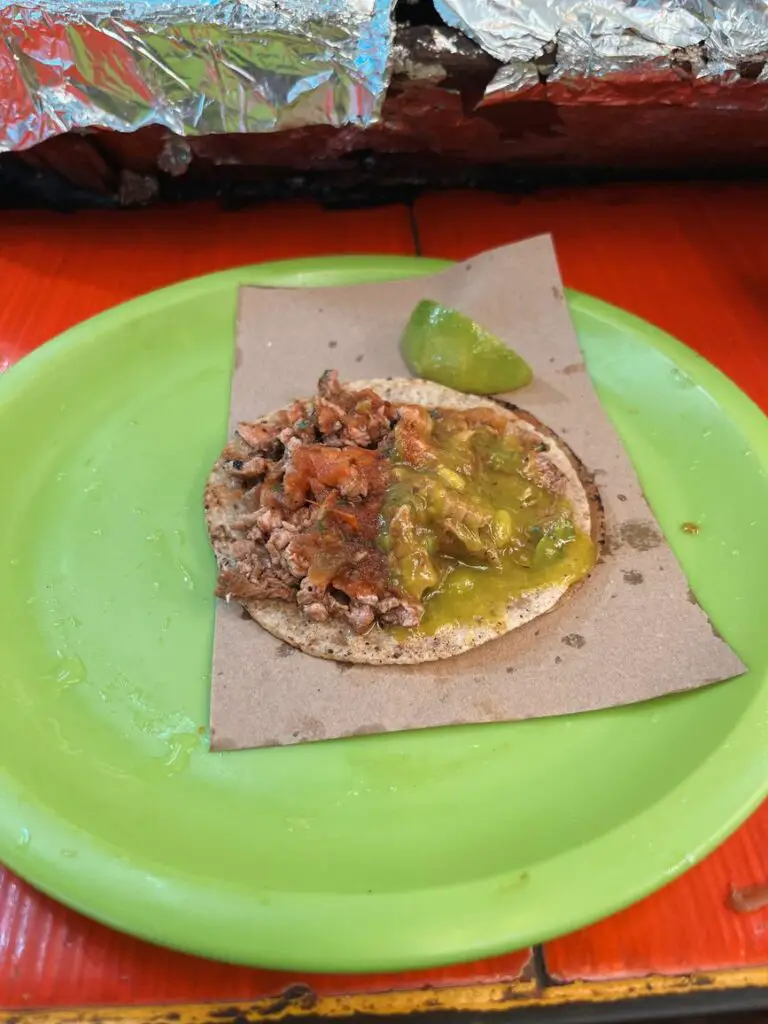Close-up of a taco with green salsa and lime on a street food tour in Merida, a must-do on your Yucatan itinerary for food lovers.