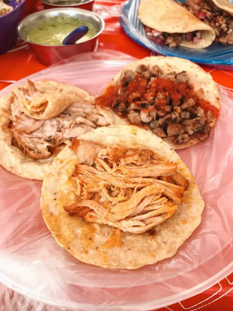 Three street tacos on a plastic-covered plate in Tulum, showcasing the delicious local cuisine in the Yucatan.