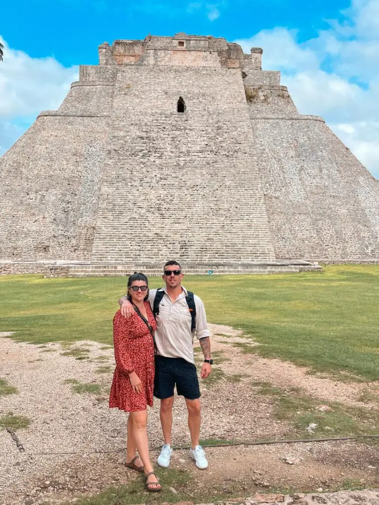 A couple - the author and her husband - standing in front of the Pyramid of the Magician at Uxmal, a significant archaeological site in Mexico.
