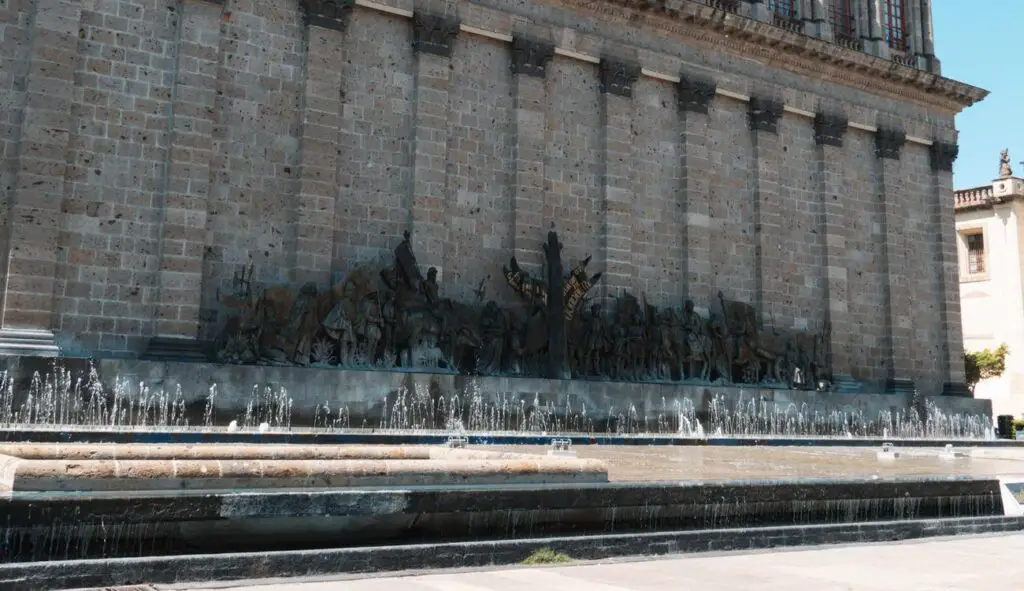A historic bronze relief mural and fountain on the wall of Teatro Degollado in Guadalajara's Plaza de Fundadores—marking the city's foundation and cultural pride.