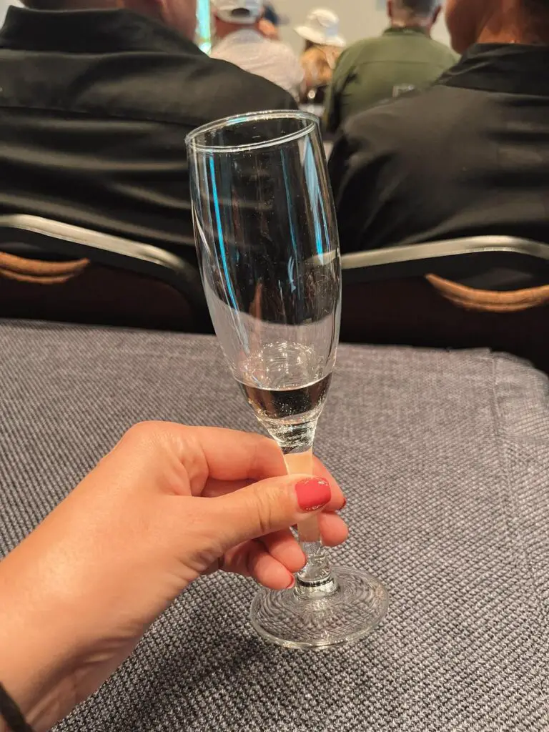 A close-up of a hand holding a champagne flute filled with tequila during a guided tasting session at the Jose Cuervo Express event.