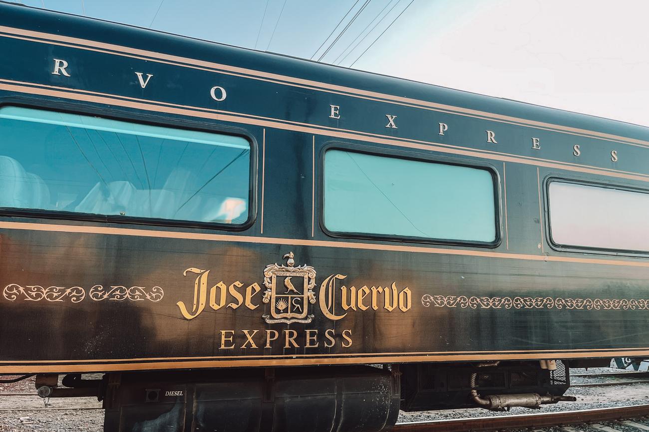 Close-up view of the luxurious black and gold Jose Cuervo Express train car on the tracks.